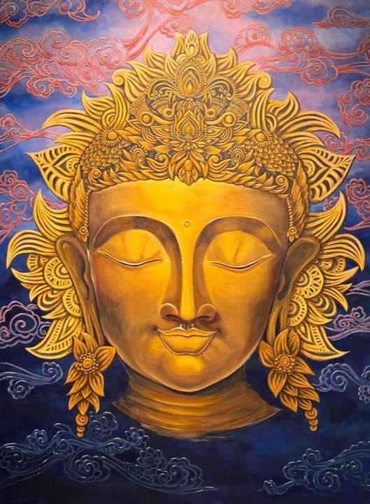 Golden Buddha face with an ornate crown against blue and pink clouds